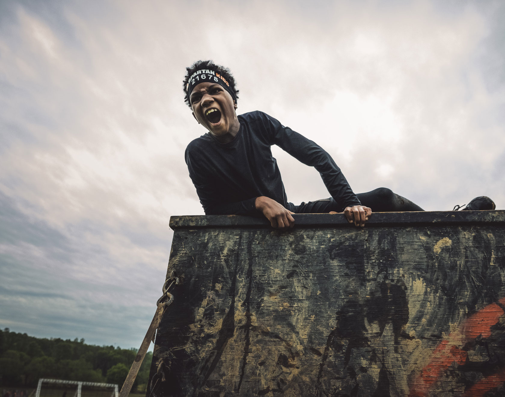 A kid trying to climb the top of an obstacle
