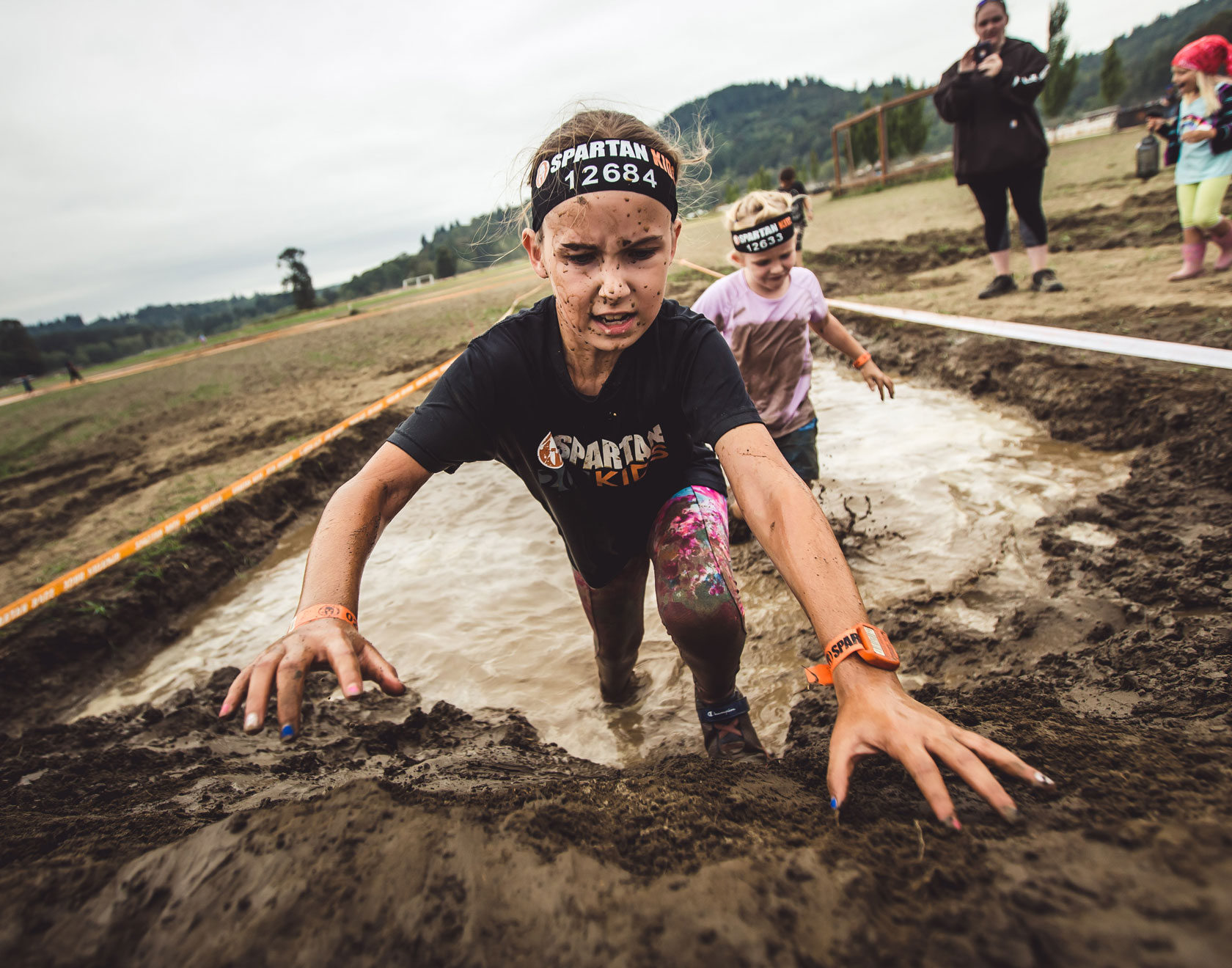 A kid participant climbing through the mud